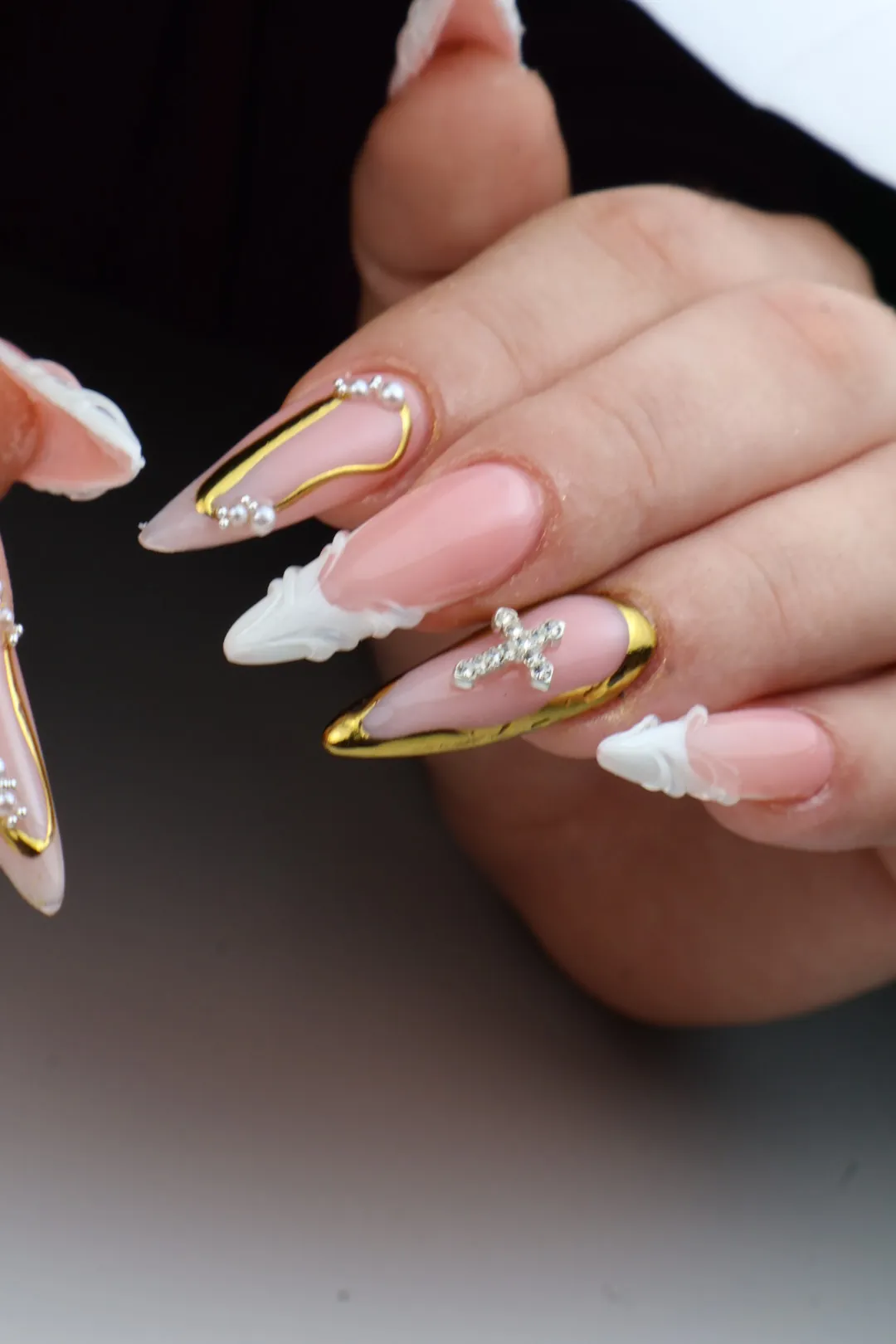 Uñas almendradas nude con líneas doradas y perlas.
