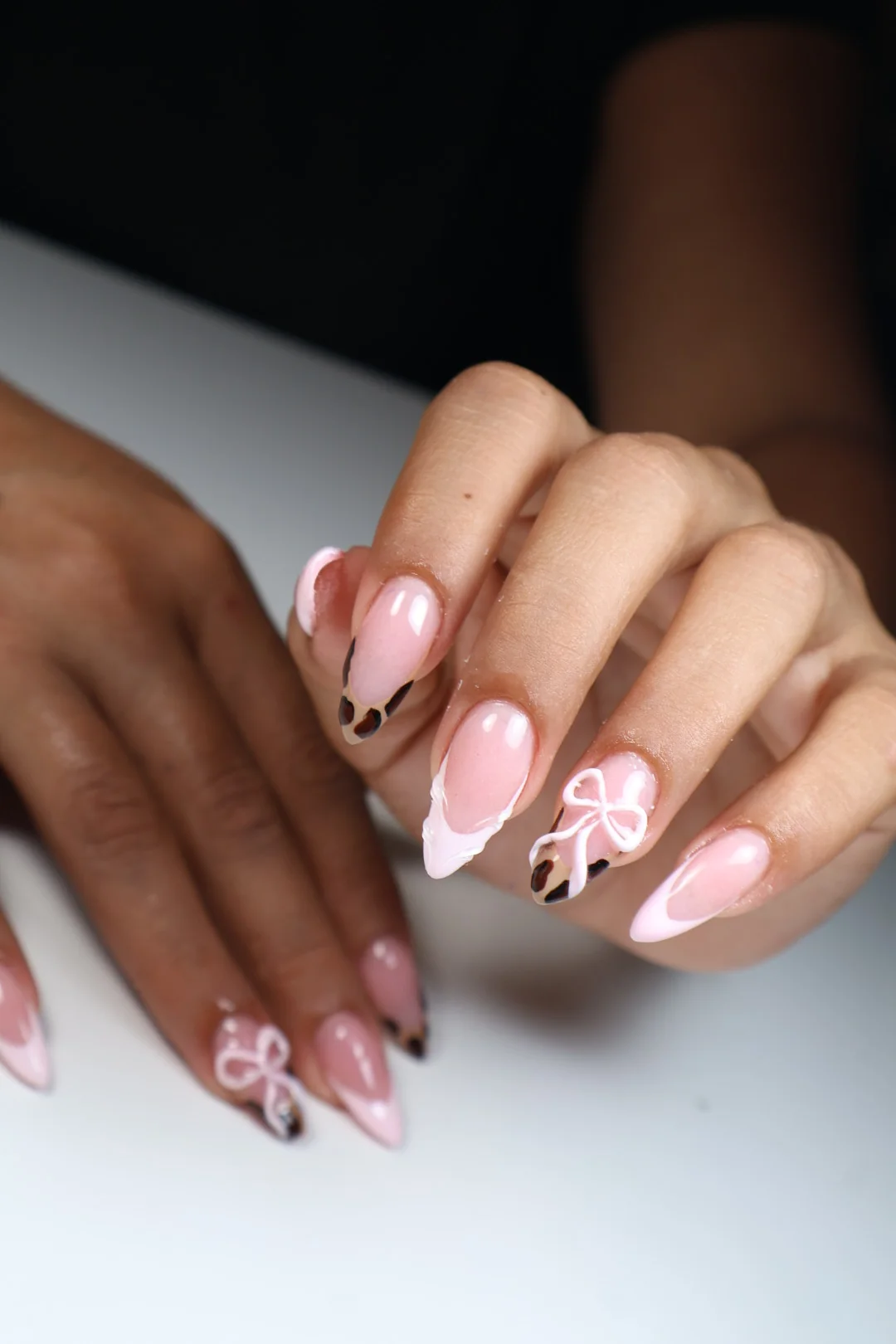 Uñas con lazos en relieve sobre base rosada.