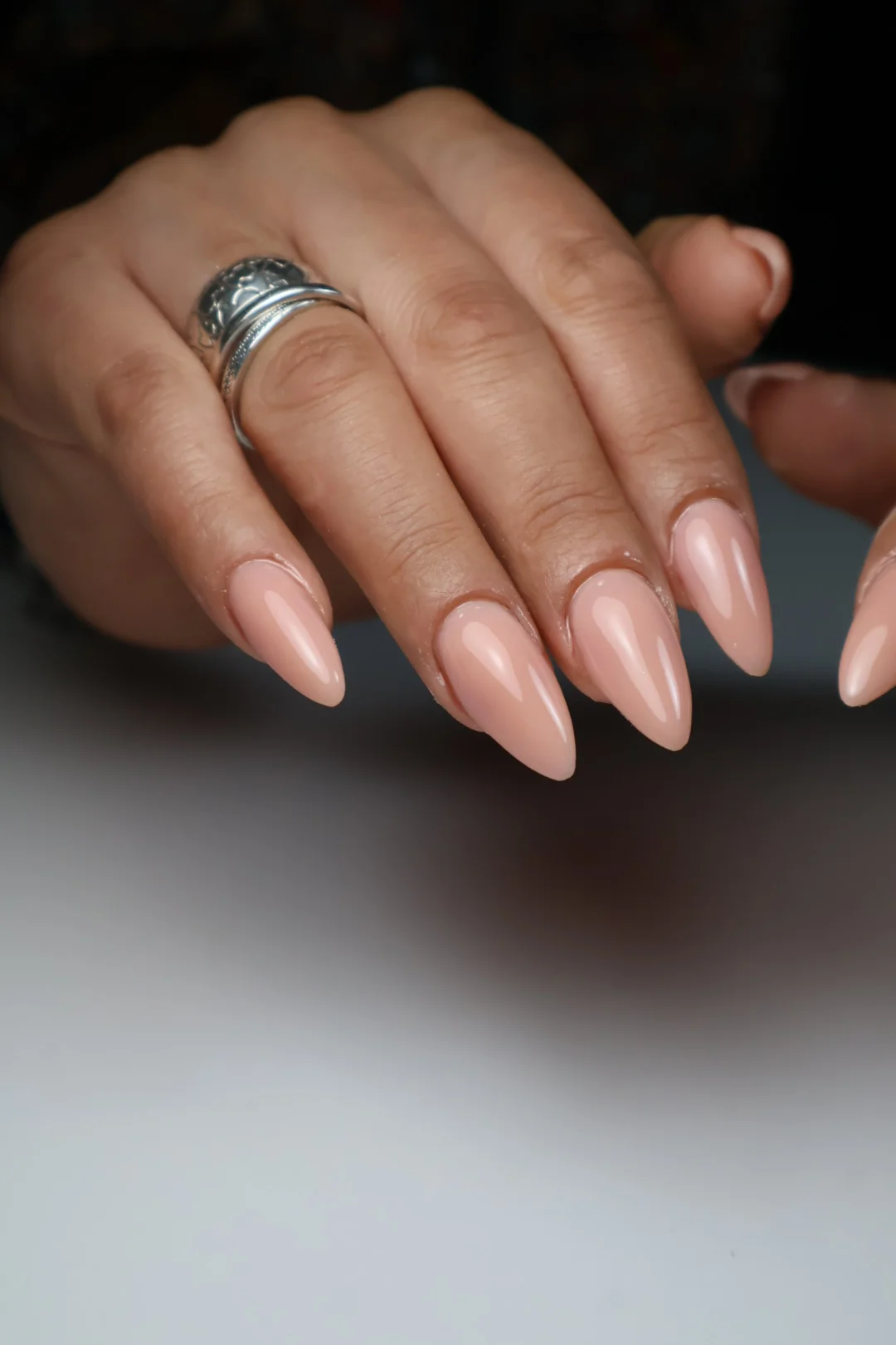 Manicura nude brillante sobre uñas almendradas.